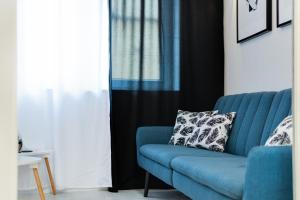 Sofá azul en la sala de estar con almohada en Crystal Apartment Katowice III, en Katowice 2 fotos más