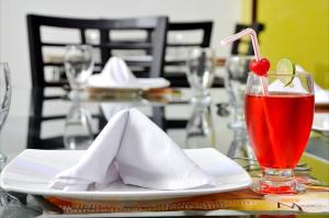 a table with a plate with a napkin and a drink at Hotel Miraflores RB in Ríohacha