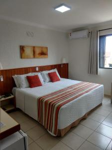 een slaapkamer met een groot bed met rode kussens bij Hotel Riviera Lins in Lins