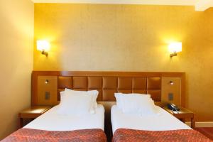 two beds in a room with two lamps on the wall at Hotel Bellevue Saint-Lazare in Paris