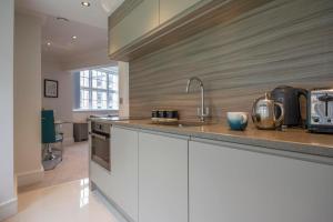 a kitchen with white cabinets and a counter top at ChocoLets - The Foss Suite in York