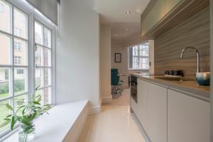 a kitchen with white cabinets and a large window at ChocoLets - The Foss Suite in York