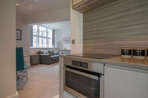 a kitchen with a stove and a living room at ChocoLets - The Foss Suite in York