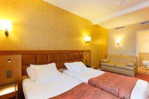 a hotel room with two beds and a couch at Hotel Bellevue Saint-Lazare in Paris