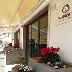 ein Gebäude mit roten Blumen vor einem Laden in der Unterkunft B&B la Maison in Sammichele di Bari
