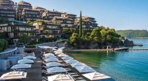 a row of white umbrellas on a beach near the water at Villa Pedja Zec Exclusive 3+ in Budva