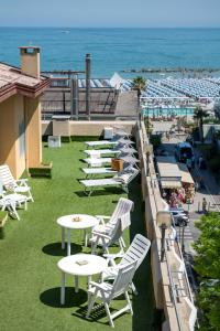 eine Reihe von weißen Tischen und Stühlen am Strand in der Unterkunft Hotel Cristina Corona in Cattolica
