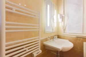 a white bathroom with a sink and a mirror at Hotel Bellevue Saint-Lazare in Paris