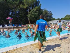 un hombre de pie en una piscina con una multitud de personas en Camping Officiel Siblu Le Bois Dormant, en Saint-Jean-de-Monts