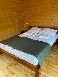 Bett in einem Zimmer mit Holzwänden in der Unterkunft Готельний комплекс БУДИНОК РИБАКА in Sataniw