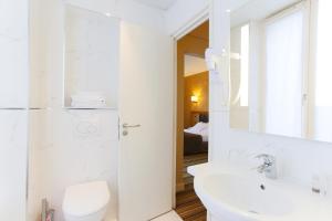 a white bathroom with a toilet and a sink at Hotel Bellevue Saint-Lazare in Paris