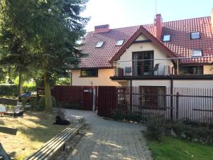a house with a fence and two cats sitting in the yard at Vertigo Narie in Morąg