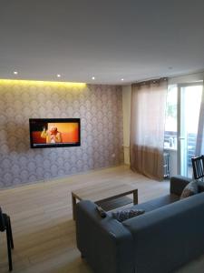 un salon avec un canapé et une télévision sur un mur dans l'établissement Studija Centre, à Klaipėda
