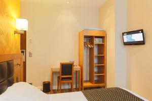a bedroom with a bed and a desk and a television at Hotel Bellevue Saint-Lazare in Paris