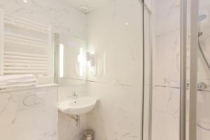 a white bathroom with a sink and a shower at Hotel Bellevue Saint-Lazare in Paris