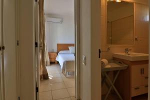 ein Badezimmer mit einem Waschbecken und ein Schlafzimmer mit einem Bett in der Unterkunft Casa Vale do Lobo 32 - Charming Townhouse AC 2 minutes walk from Beach Praca in Vale do Lobo