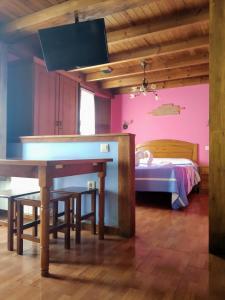 Habitación con mesa y cama con paredes rosas. en Apartamentos Aguasaliu, en Ponga