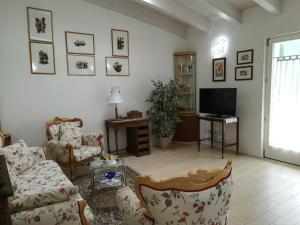 ein Wohnzimmer mit einem Sofa, Stühlen und einem TV in der Unterkunft Ferrarini in Riva del Garda