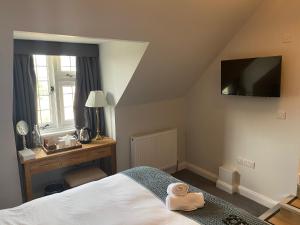 a bedroom with a bed and a desk and a television at Three Bishops Inn in Newport
