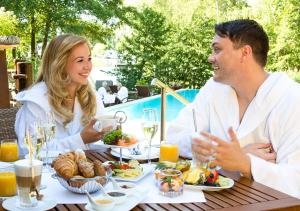 mężczyzna i kobieta siedzący przy stole jedzący jedzenie w obiekcie SATAMA Sauna Resort & SPA w mieście Wendisch Rietz