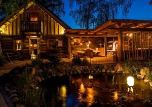 une cabane en rondins avec un étang en face de celle-ci dans l'établissement SATAMA Sauna Resort & SPA, à Wendisch Rietz