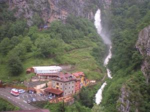 a building on the side of a mountain with a waterfall at Hotel Puente Vidosa in Amieva