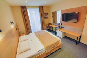 a bedroom with a bed and a desk and a television at Sport Hotel 1 in Cherkasy