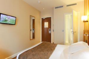 a bedroom with a bed and a tv on the wall at Hotel Bellevue Saint-Lazare in Paris