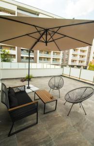 a patio with two tables and a large umbrella at Gente Apartments in Cluj-Napoca