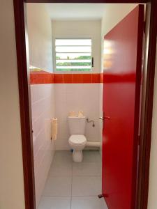 a bathroom with a toilet and a red door at L OREE DU BOIS in Cayenne
