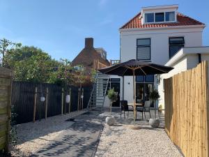 un patio con sombrilla frente a una casa en Casa TX21, en Den Burg