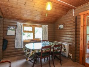 comedor en una cabaña de madera con mesa y sillas en Millmore Cabin, en Killin