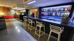 a bar with four stools and a counter with drinks at Hotel Metrò in Milan