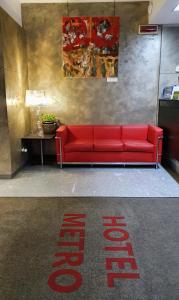 un divano rosso in una stanza con un cartello sul pavimento di Hotel Metrò a Milano