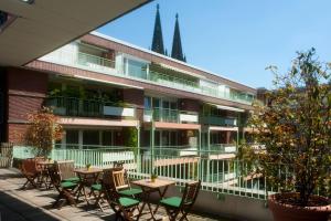 an outdoor patio with tables and chairs in front of a building at Residenz am Dom Boardinghouse Apartments in Cologne