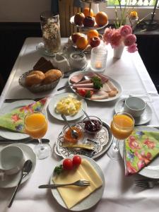 a table with plates of food and glasses of orange juice at Hotel-Restaurant Kranefoer in Waltrop