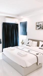 two beds in a white bedroom with black curtains at Icare Residence & Hotel in Bangkok