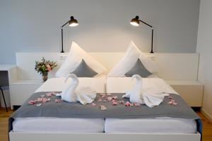 due cigni seduti sopra un letto con fiori di Hotel Brandenburger Dom a Brandenburg an der Havel