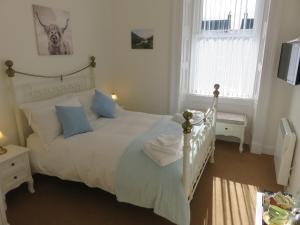 a bedroom with a white bed with blue pillows at Bankhouse B&B in Aberlour