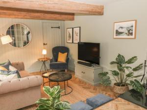 sala de estar con sofá y TV en Overlea Cottage, en Highpeak Junction