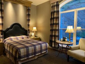 a hotel room with a bed and a chair and a window at Celebrity Hotel in Deadwood