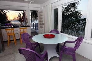 a table and purple chairs in a room with a balcony at Saint Germain Kite Residence in Icaraí