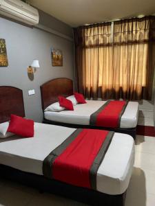 2 Betten in einem rot-weißen Zimmer in der Unterkunft Stada Hotel kubang kerian in Kota Bharu