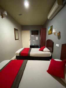 2 Betten in einem Hotelzimmer mit roten Kissen in der Unterkunft Stada Hotel kubang kerian in Kota Bharu