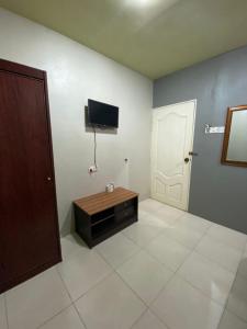 Zimmer mit einem TV, einer Tür und Fliesenboden in der Unterkunft Stada Hotel kubang kerian in Kota Bharu