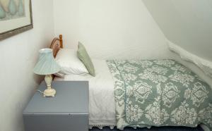 a bedroom with a bed and a nightstand with a lamp at The Burrow in Chideock