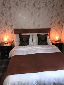 a bedroom with a large bed with two lamps at Woodvale in Balloch