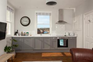 una cocina con un reloj en la pared junto a una ventana en The Drawing Office, en Berwick-Upon-Tweed