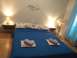a bedroom with a blue bed with towels and a fan at Apartments Vidic in Orebić