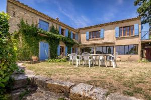 een tafel en stoelen voor een gebouw bij MAISON AVEC PISCINE - PROCHE AVIGNON - WiFI GRATUIT in Sauveterre